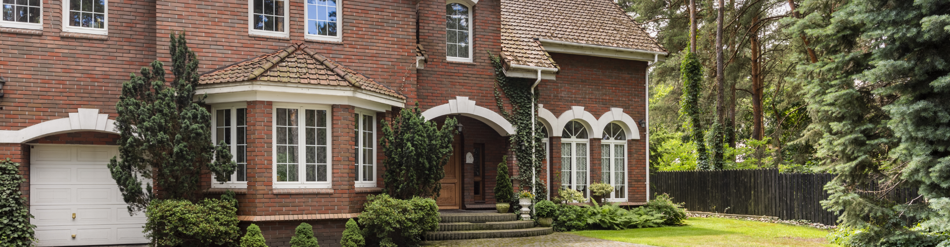Well-maintained brick residential home with arched windows and landscaped garden